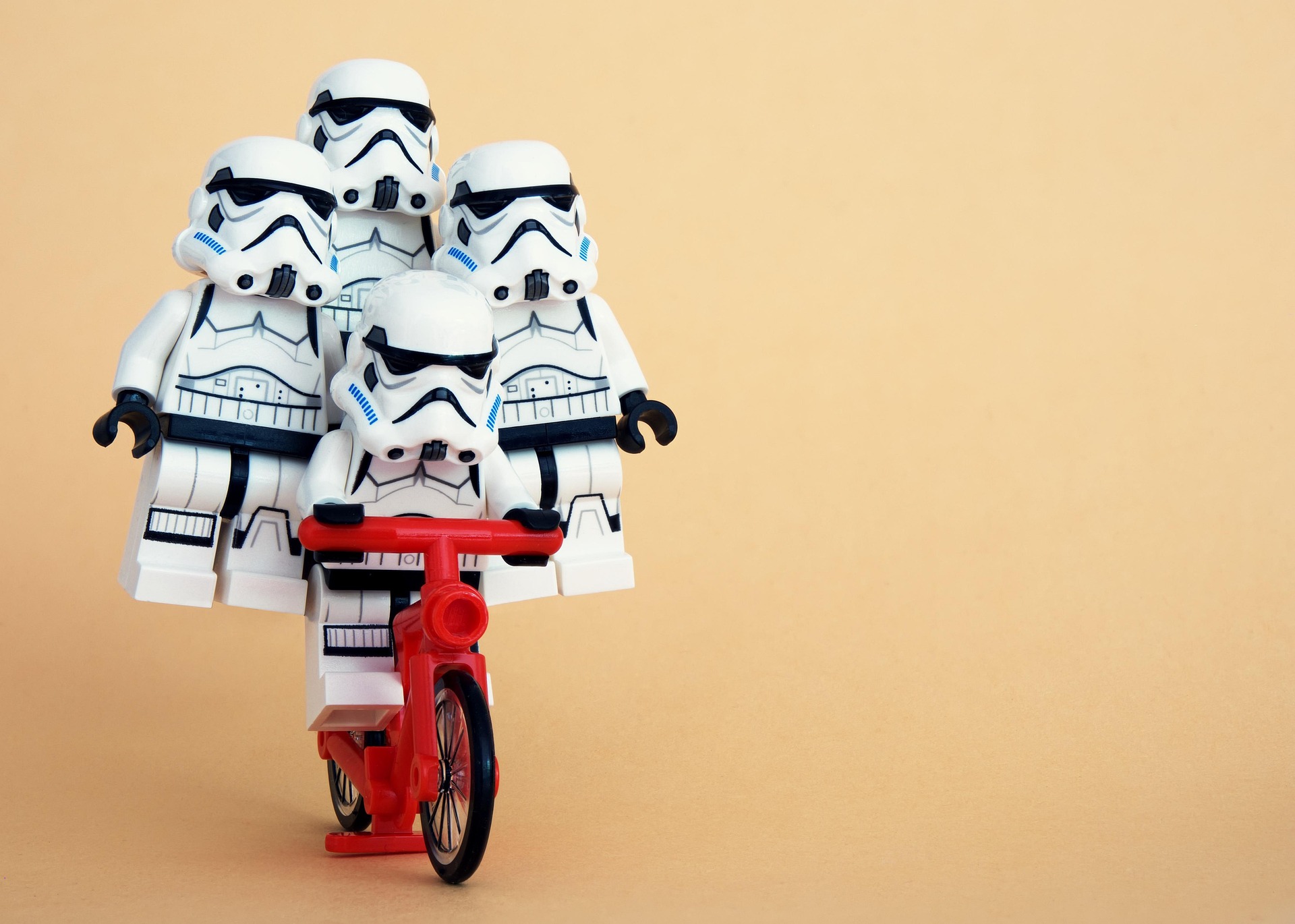 LEGO Stormtrooper minifigures riding together on a small red bicycle